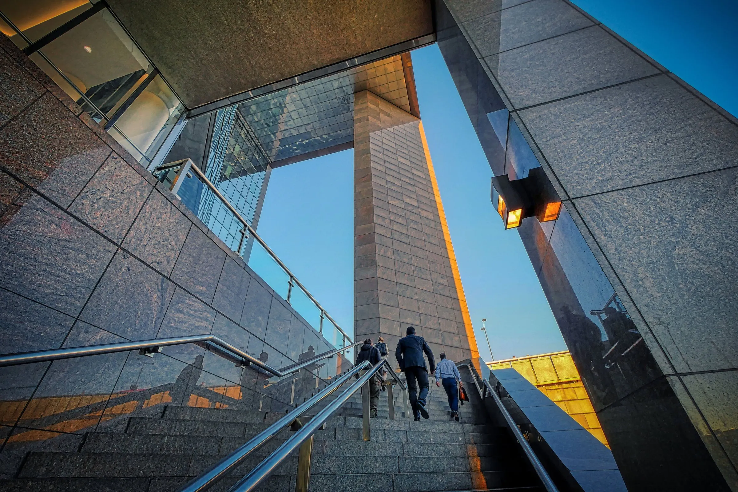 People in business dress climbing steps between office towers at sunrise